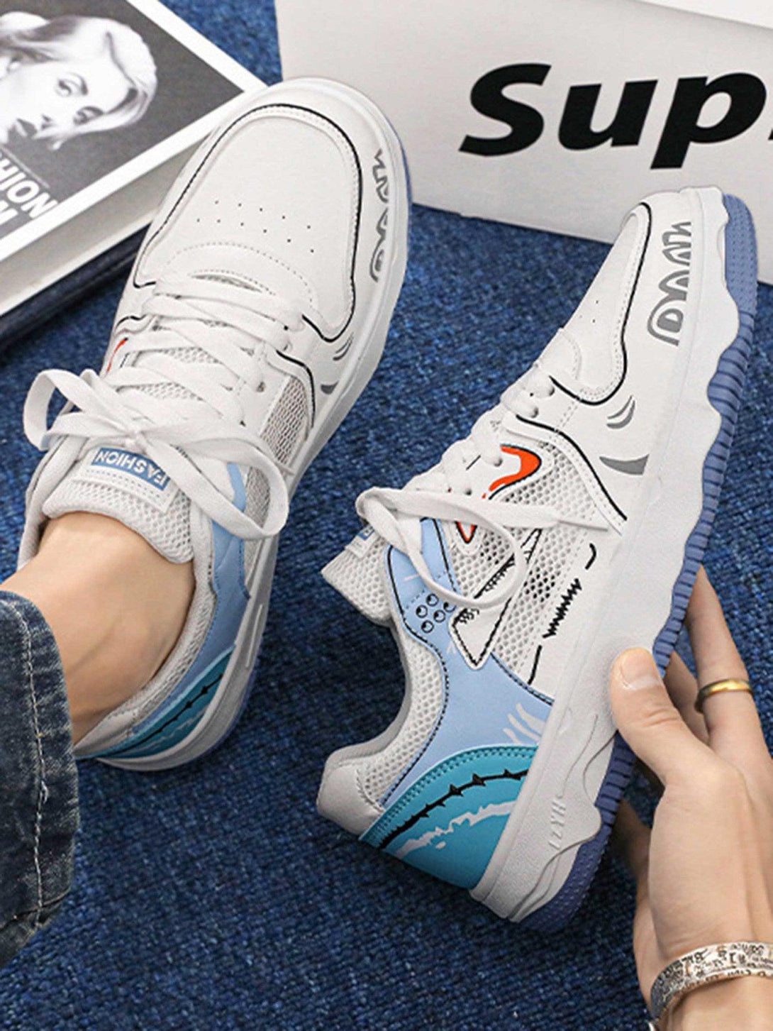 TALISHKO mesh board shoes with unique graphics and blue accents, worn casually with denim.