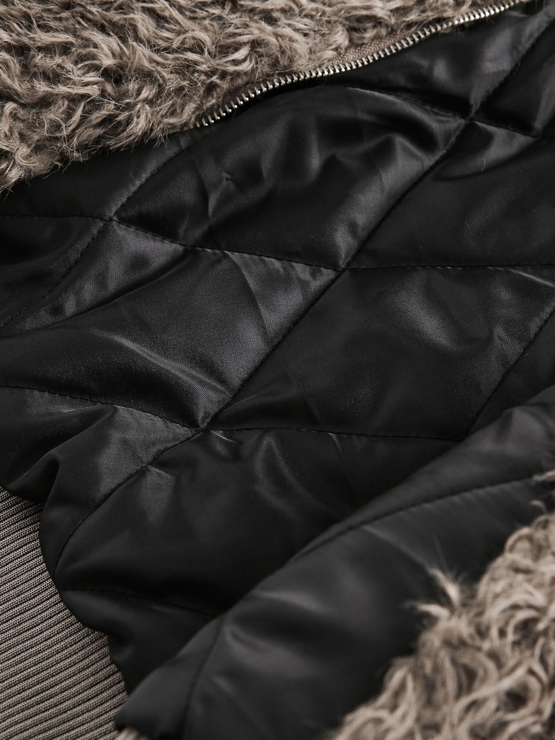 Detailed fabric and stitching of a faux fur jacket's inner lining by TALISHKO.