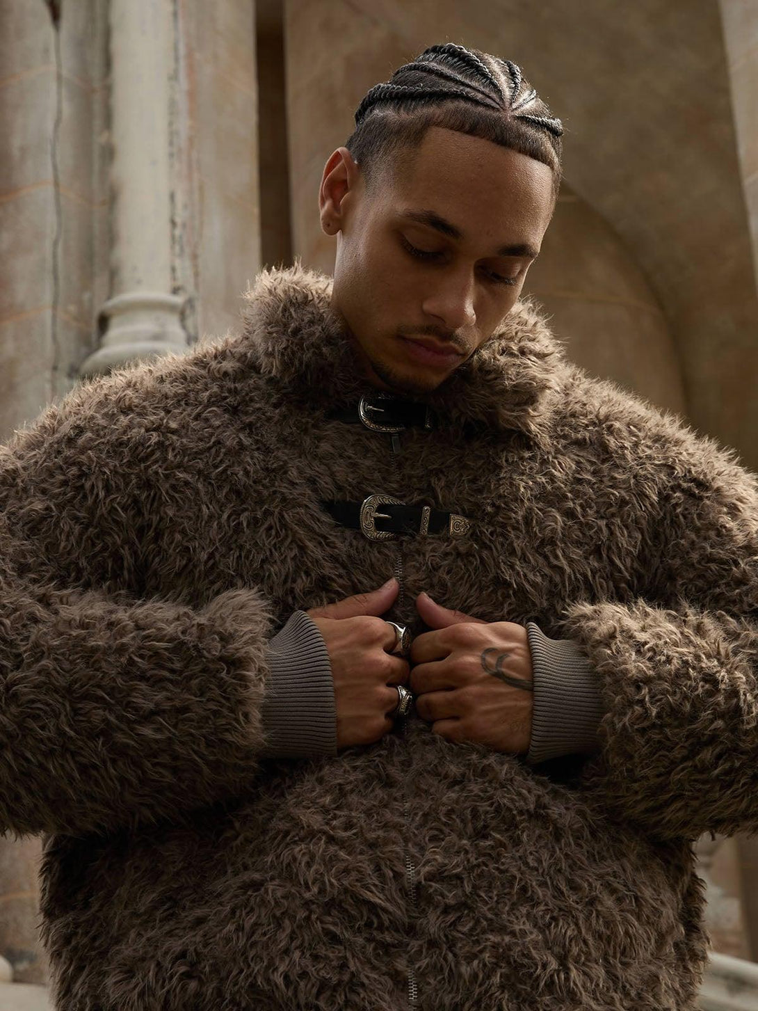 Model wearing a plush faux fur jacket with metal leather buckles, styled by TALISHKO.