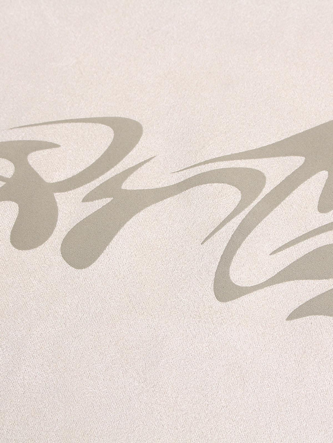 A tight crop highlighting TALISHKO's metallic print on beige suede, showcasing intricate design.