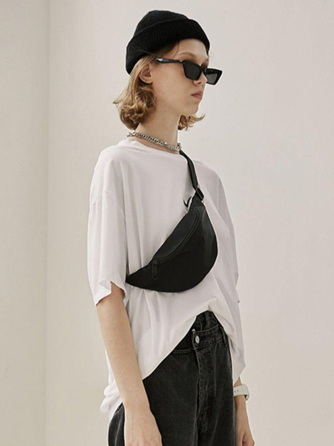 Model in a casual look with a black mini crossbody waist bag and beanie by TALISHKO.