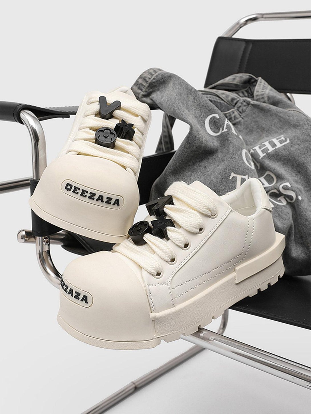 Monochrome chunky tread sneakers by TALISHKO on a chair, highlighting bold laces and design.
