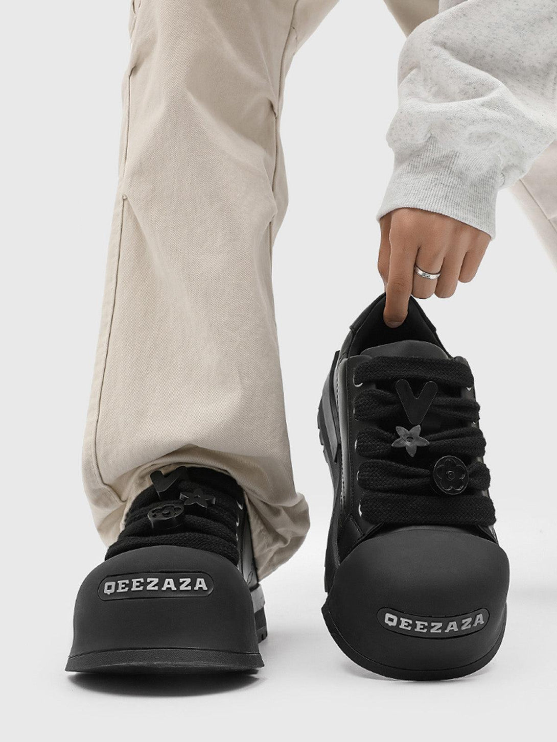 Monochrome chunky tread sneakers by TALISHKO, worn with beige pants, showcasing bold laces.