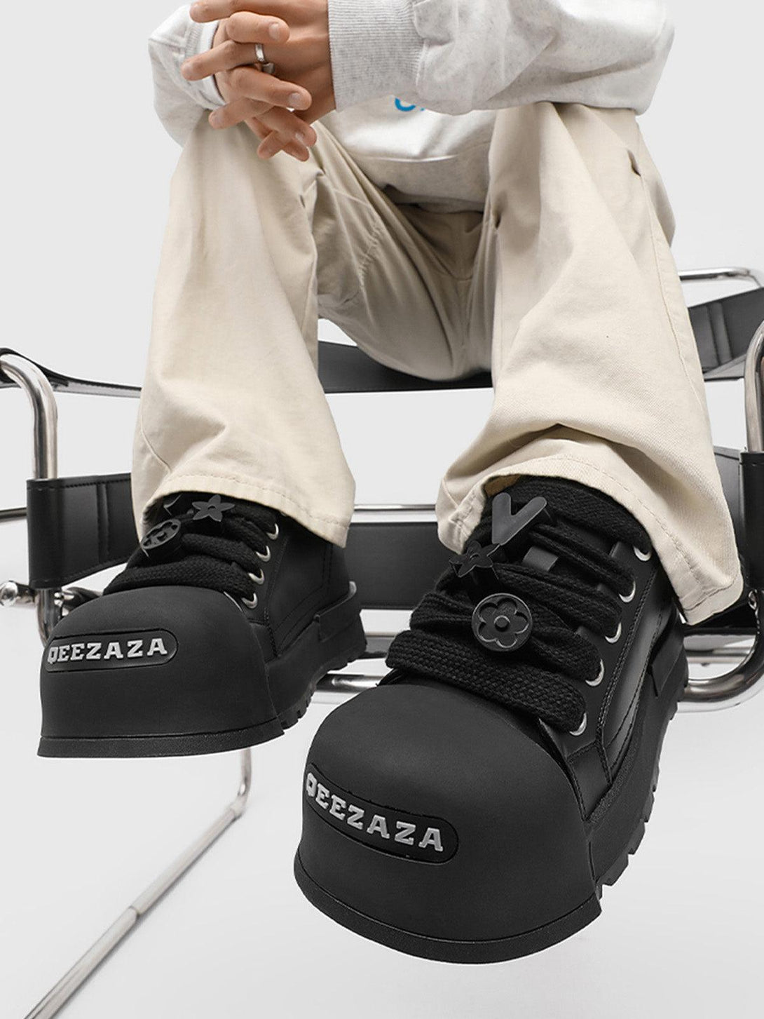TALISHKO's monochrome chunky tread sneakers in black, paired with beige pants, for a modern look.