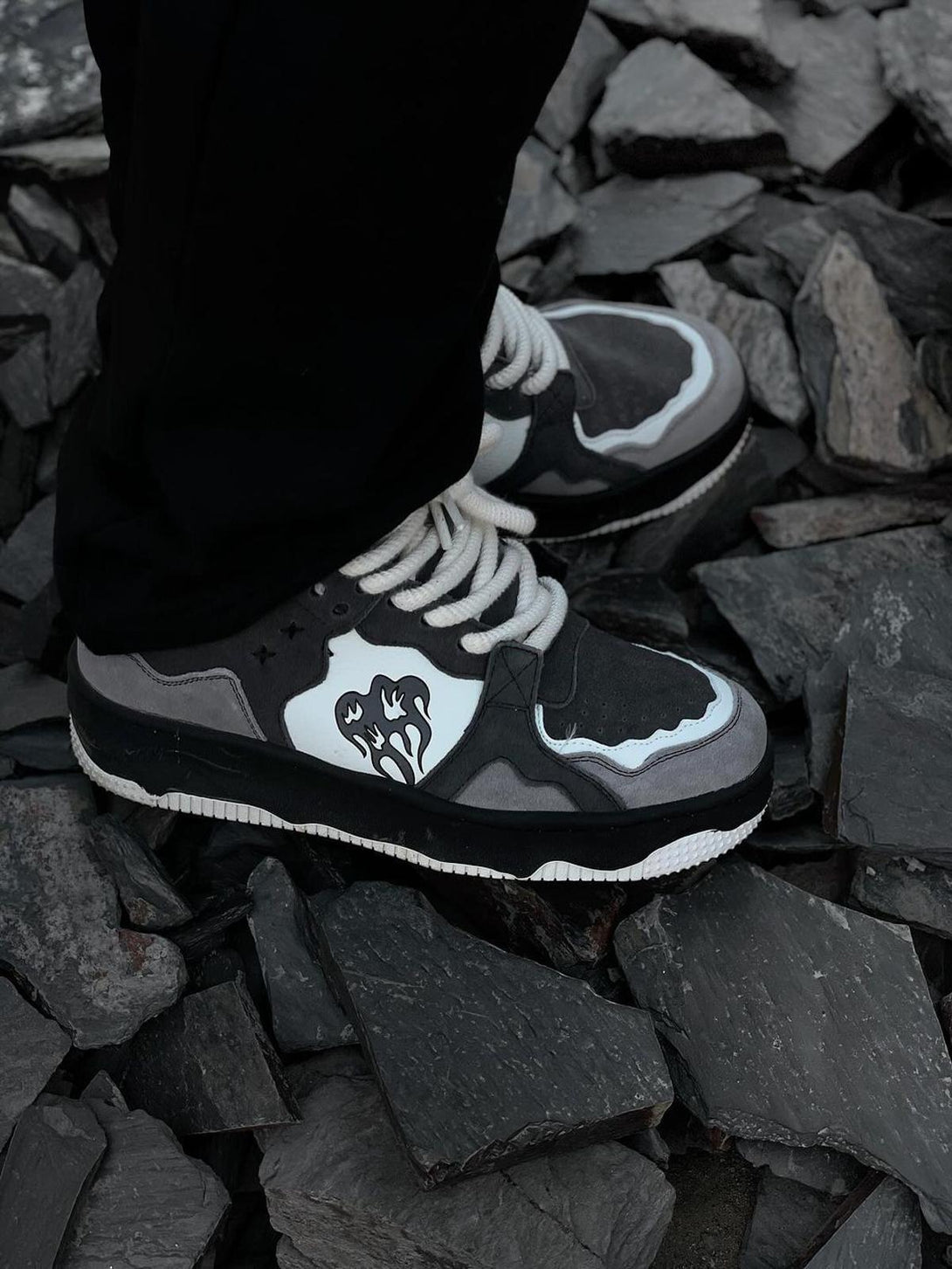 TALISHKO sneakers on rugged stone, showcasing bold monochrome design and intricate details.