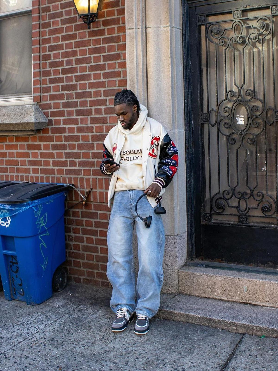 Streetwear look featuring TALISHKO sneakers paired with casual jeans and a varsity jacket.