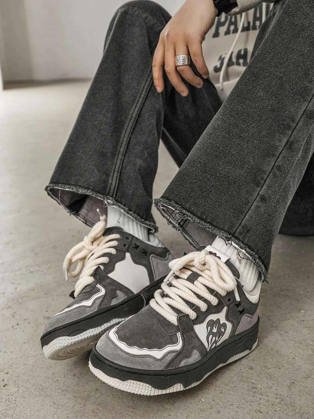 Street-inspired TALISHKO sneakers with bold laces and flame detail paired with dark jeans.