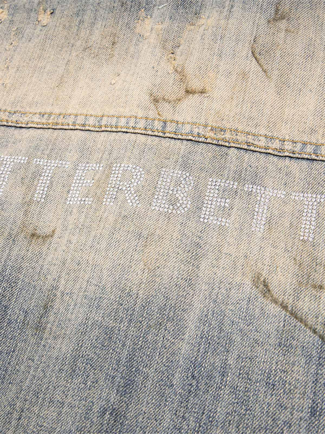 Intricate look at rhinestone detailing on mud-dyed distressed denim by TALISHKO.