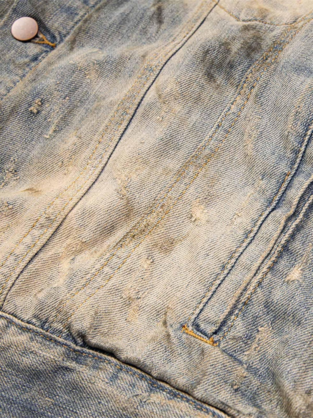 A tight crop highlighting the mud-dyed distressed denim texture and stitching by TALISHKO.