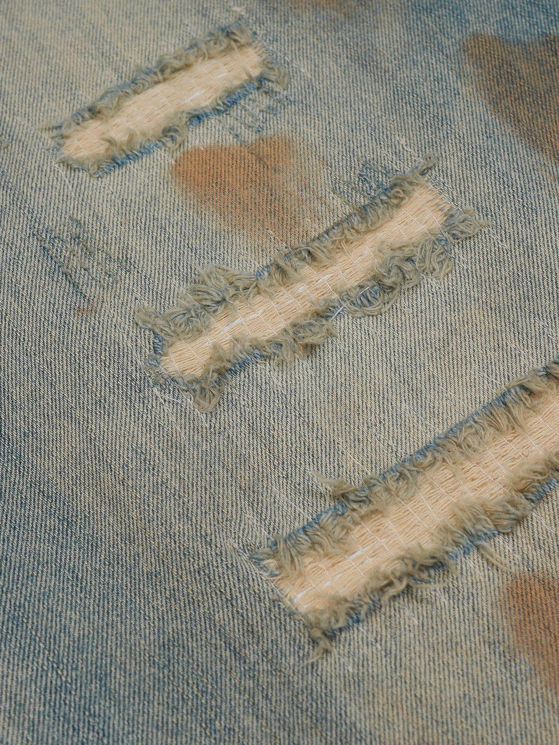 Intricate look at TALISHKO jeans' distressed fabric with vintage fade and mud dyeing details.