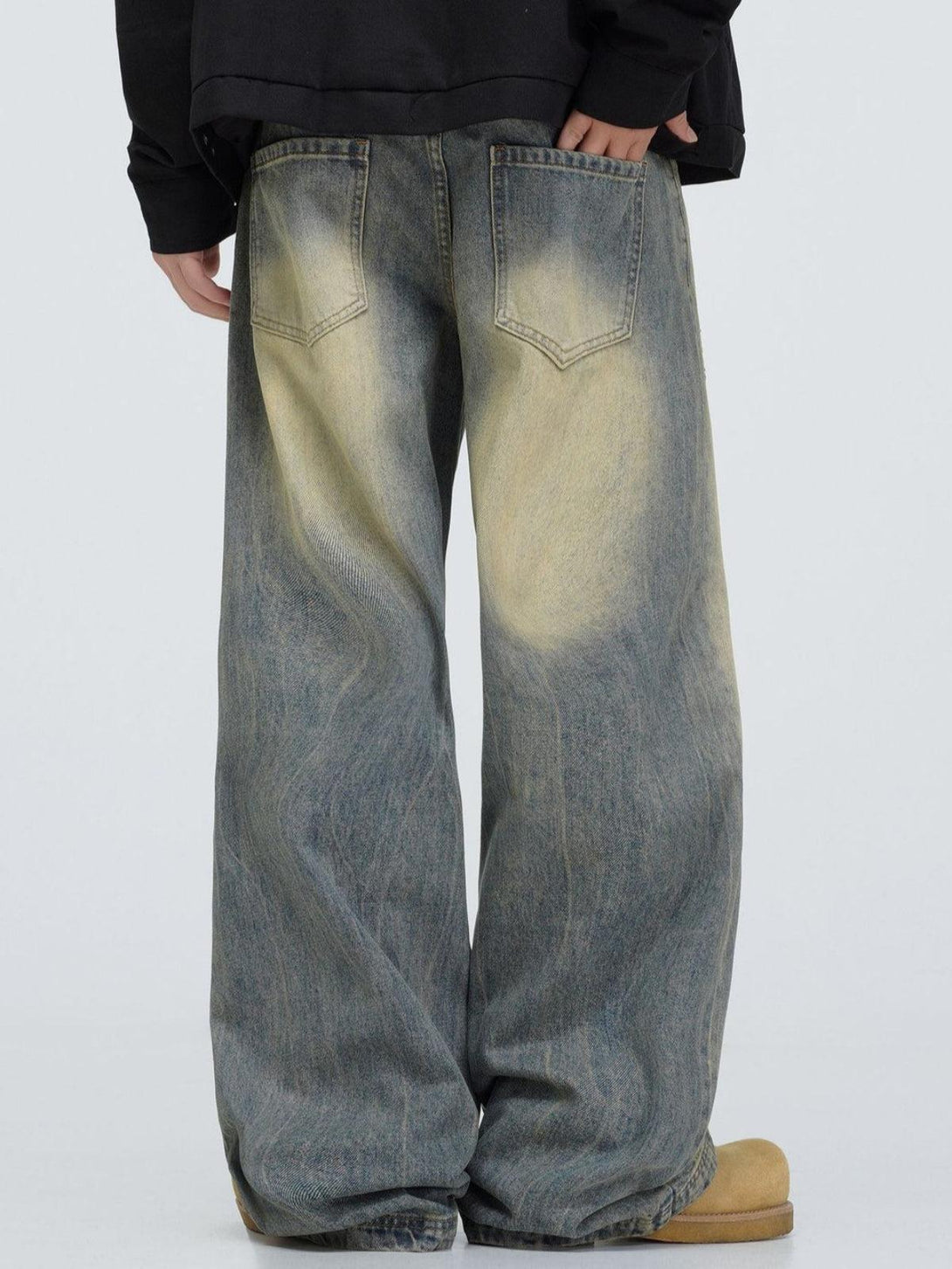 Back view of TALISHKO mud dyeing jeans, highlighting a relaxed fit and unique faded pattern.