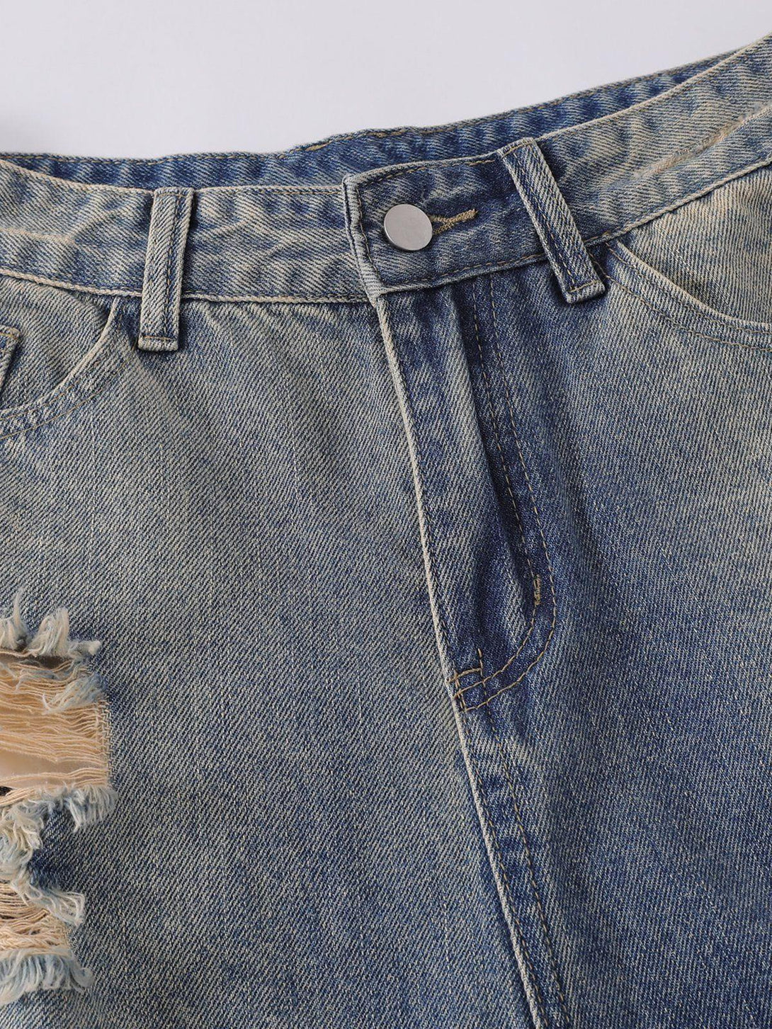 Focusing on the distressed details of TALISHKO's denim jorts, highlighting casual texture.