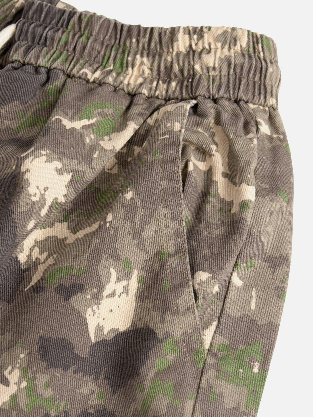 A detailed view of TALISHKO camouflage shorts highlighting the elastic waistband and pocket design.
