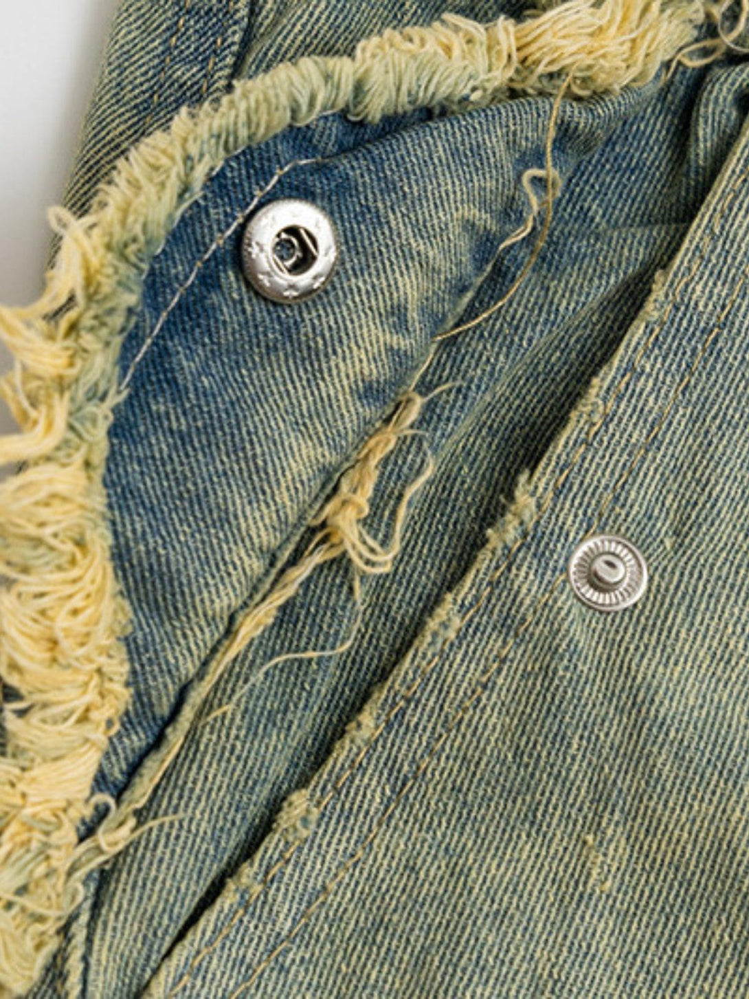 Detailed fabric and stitching on TALISHKO's multi-pocket fringe washed jeans, highlighting texture.
