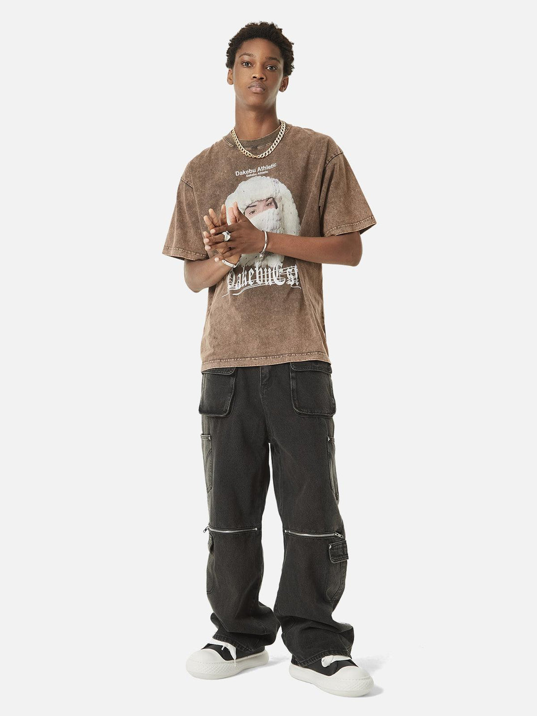 Model sporting TALISHKO hip-hop jeans with multi-pocket zippers and a brown graphic tee.
