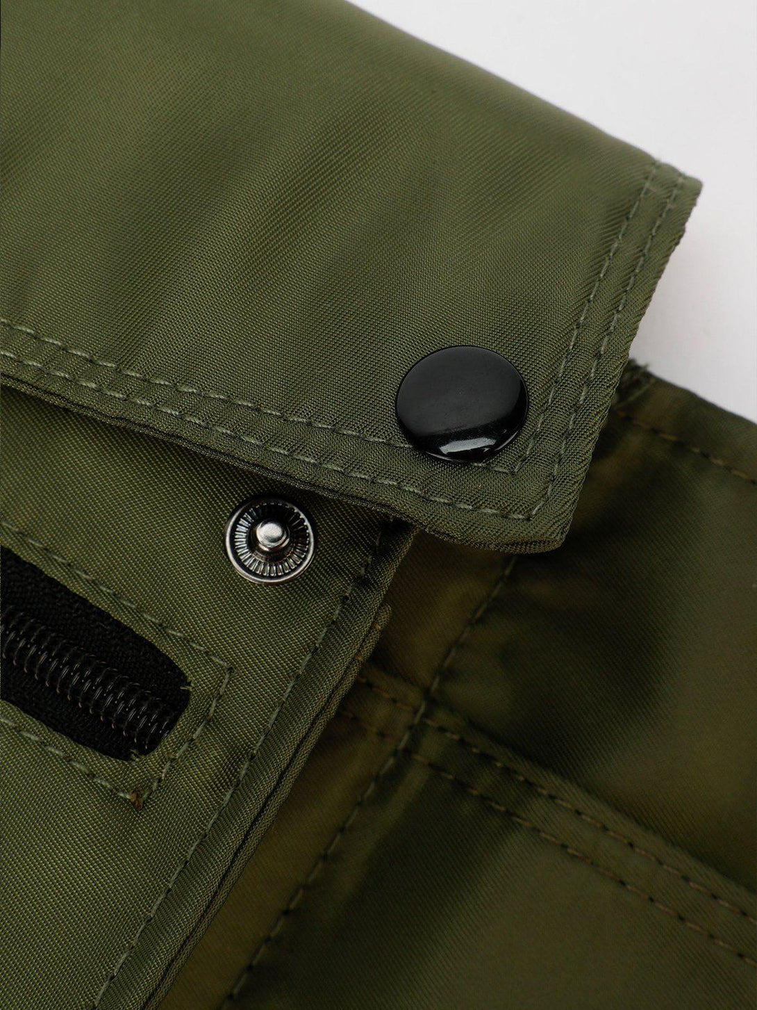 Intricate look at TALISHKO's green crossbody bag, highlighting button and zipper details.