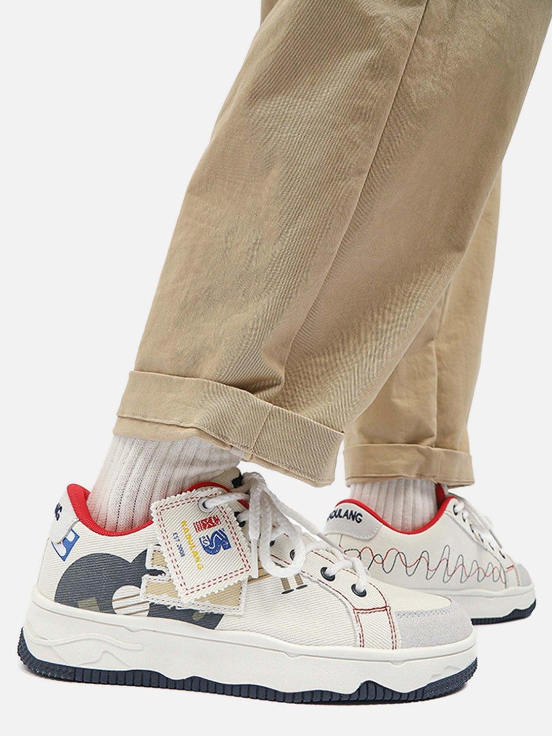 TALISHKO canvas shoes with unique graphic details and red accents, styled with beige pants.
