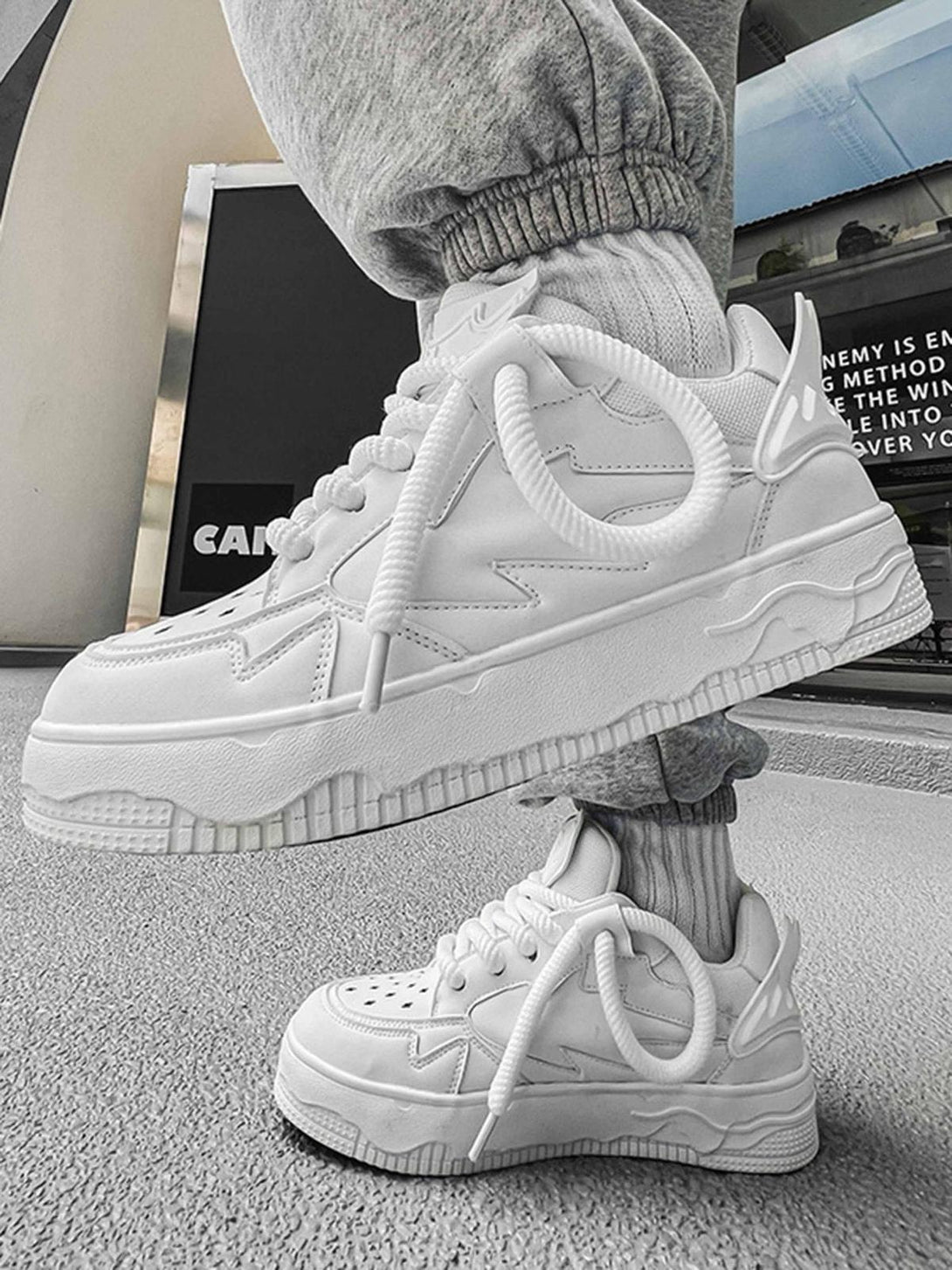 Stylish TALISHKO retro board shoes in white, worn with casual joggers, highlighting trendy design.