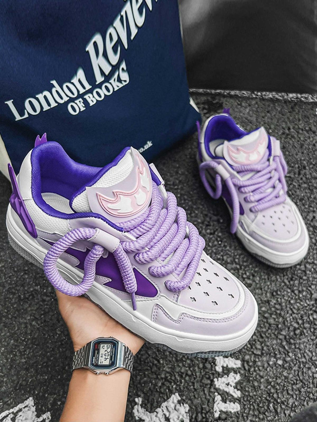 Purple TALISHKO retro board shoes held in hand, highlighting bold laces and unique design.