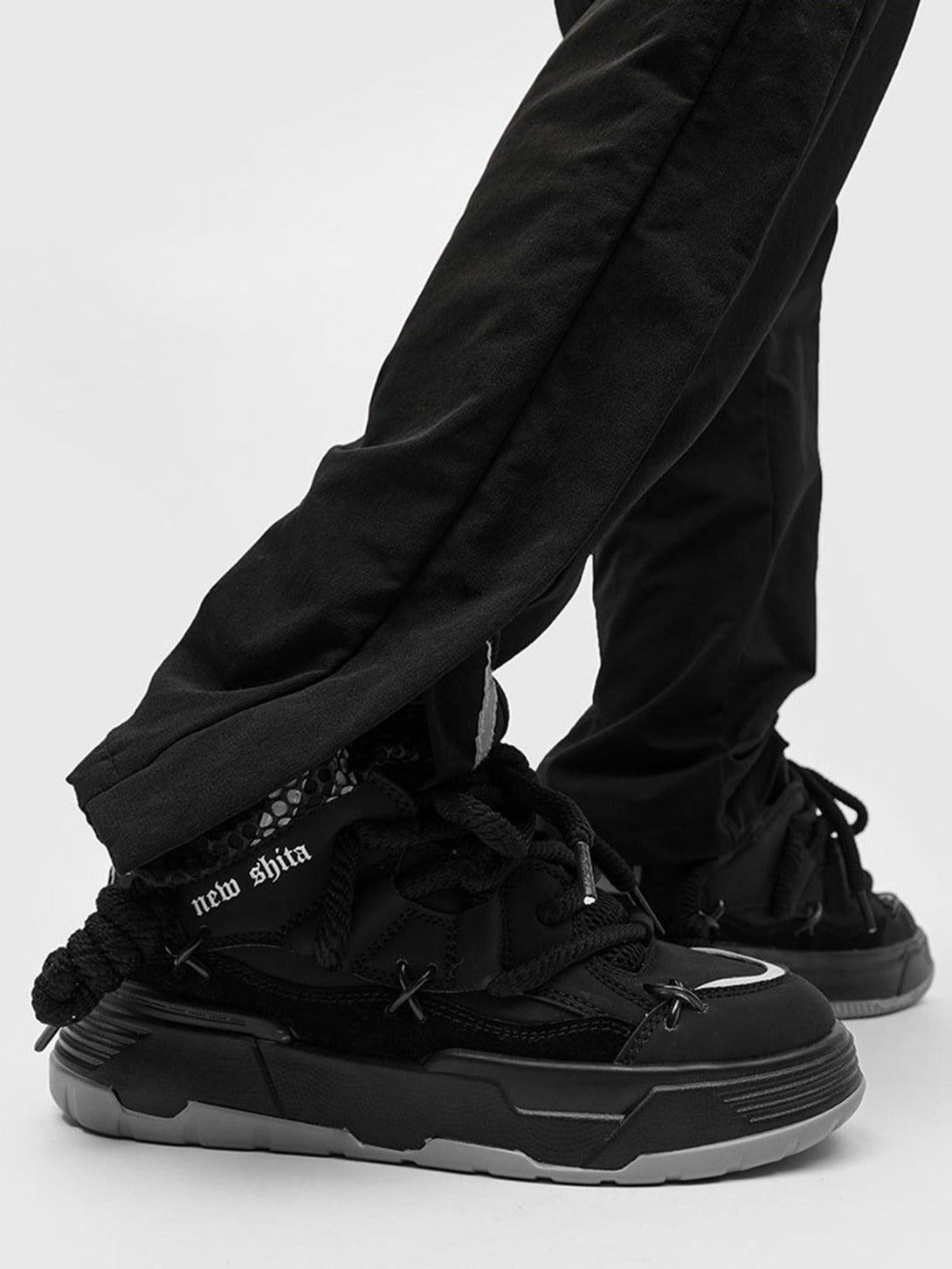 TALISHKO black board shoes with thick soles paired with black pants for a sleek urban look.