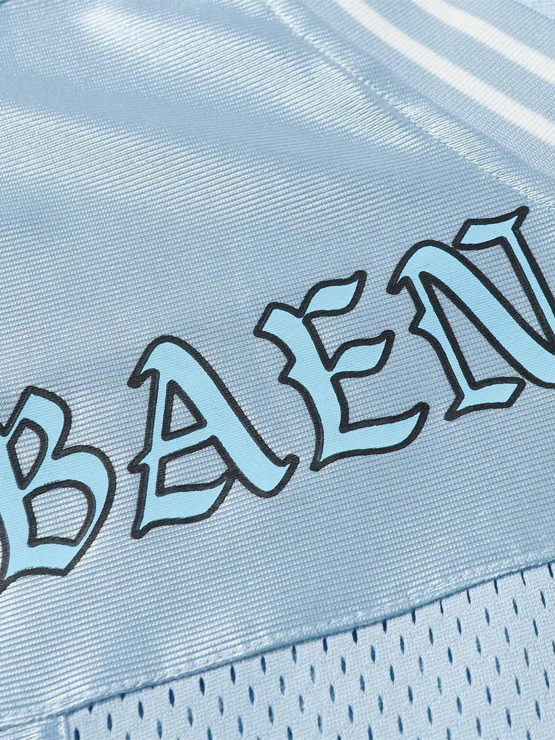 Zoomed-in texture of TALISHKO's light blue jersey, highlighting the bold lettering design.