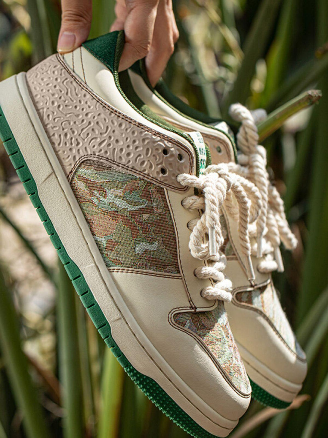 A close-up of TALISHKO skate shoes, highlighting the textured details and forest print design.