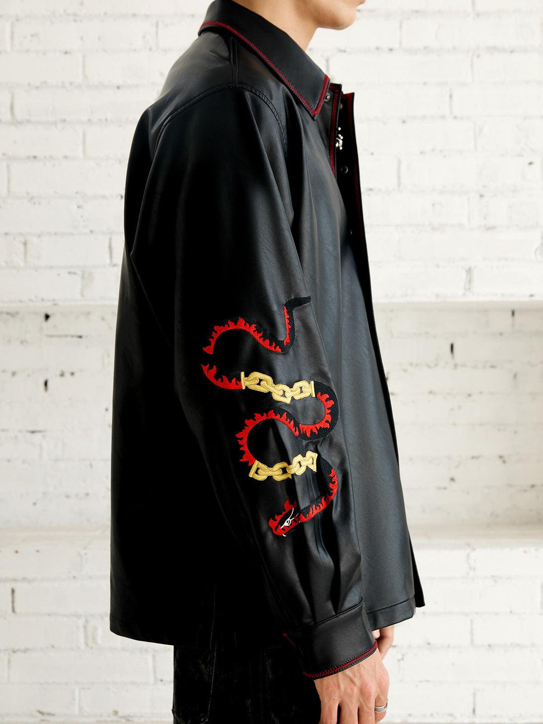 Side view of TALISHKO's embroidered leather shirt, showcasing bold chain and flame details.