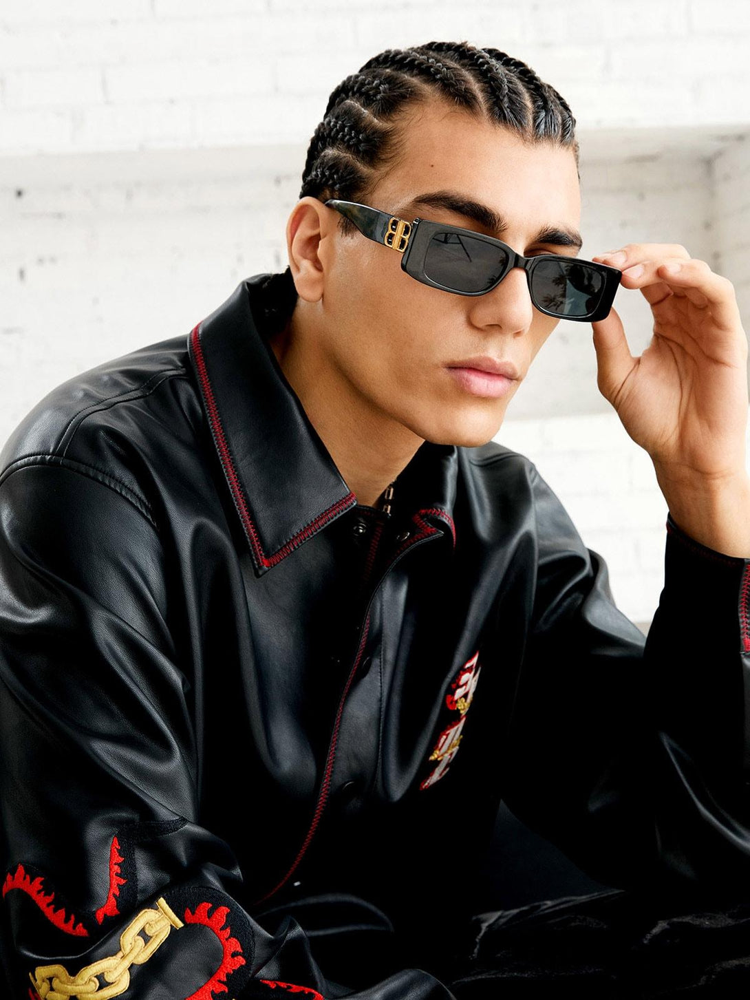 Model in TALISHKO's leather shirt with intricate embroidery, paired with sleek sunglasses.