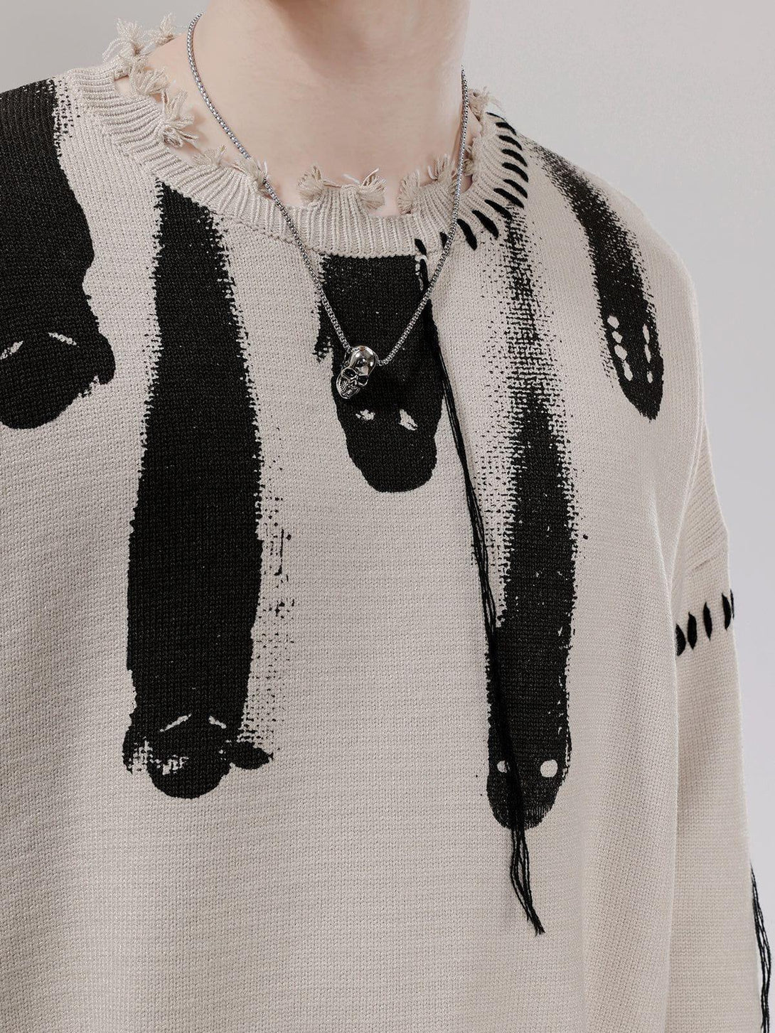 Close-up of TALISHKO sweater with abstract black pattern and distressed neckline details.