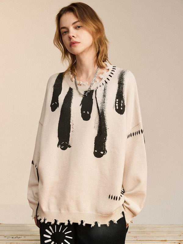 Model wearing a TALISHKO knit sweater with bold black abstract design and distressed edges.