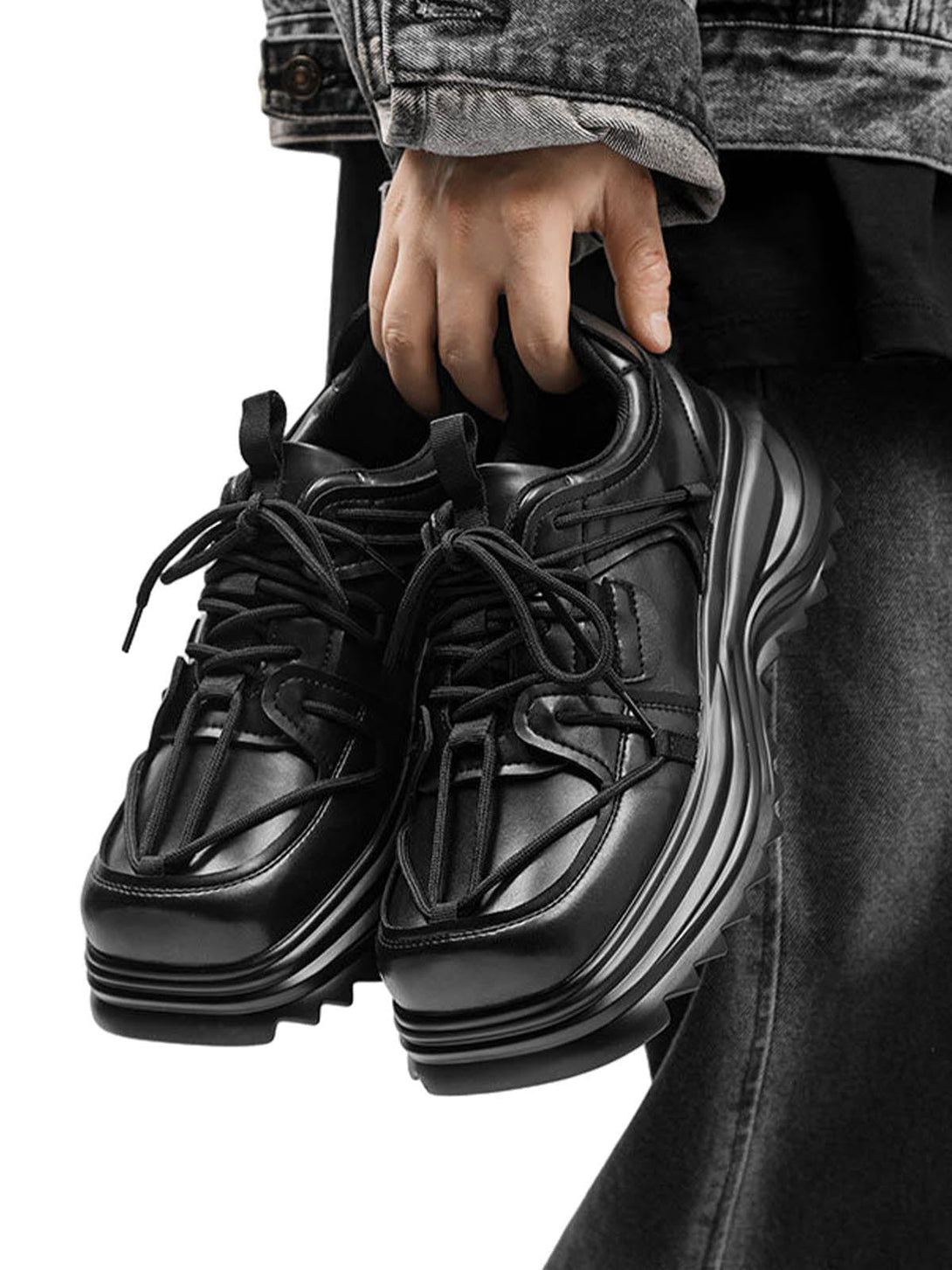 Black platform sneakers by TALISHKO, held in hand, showcasing rugged outdoor workwear style.