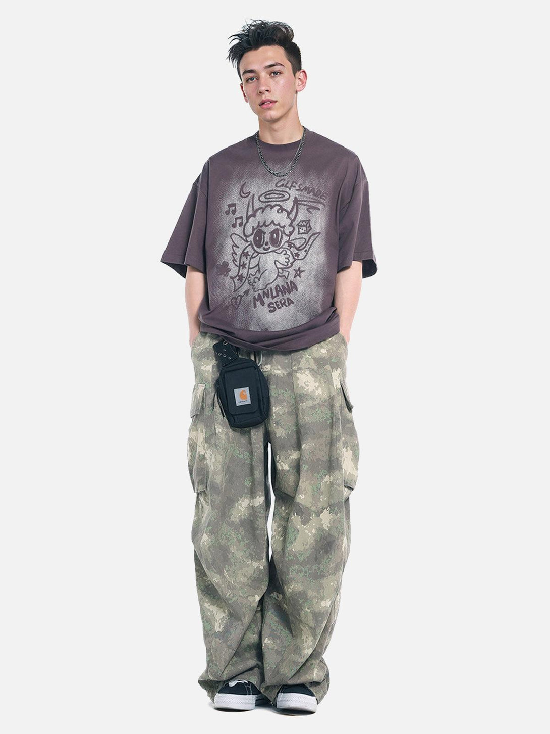 Model in TALISHKO oversized angel graphic T-shirt, styled with camo pants for casual flair.