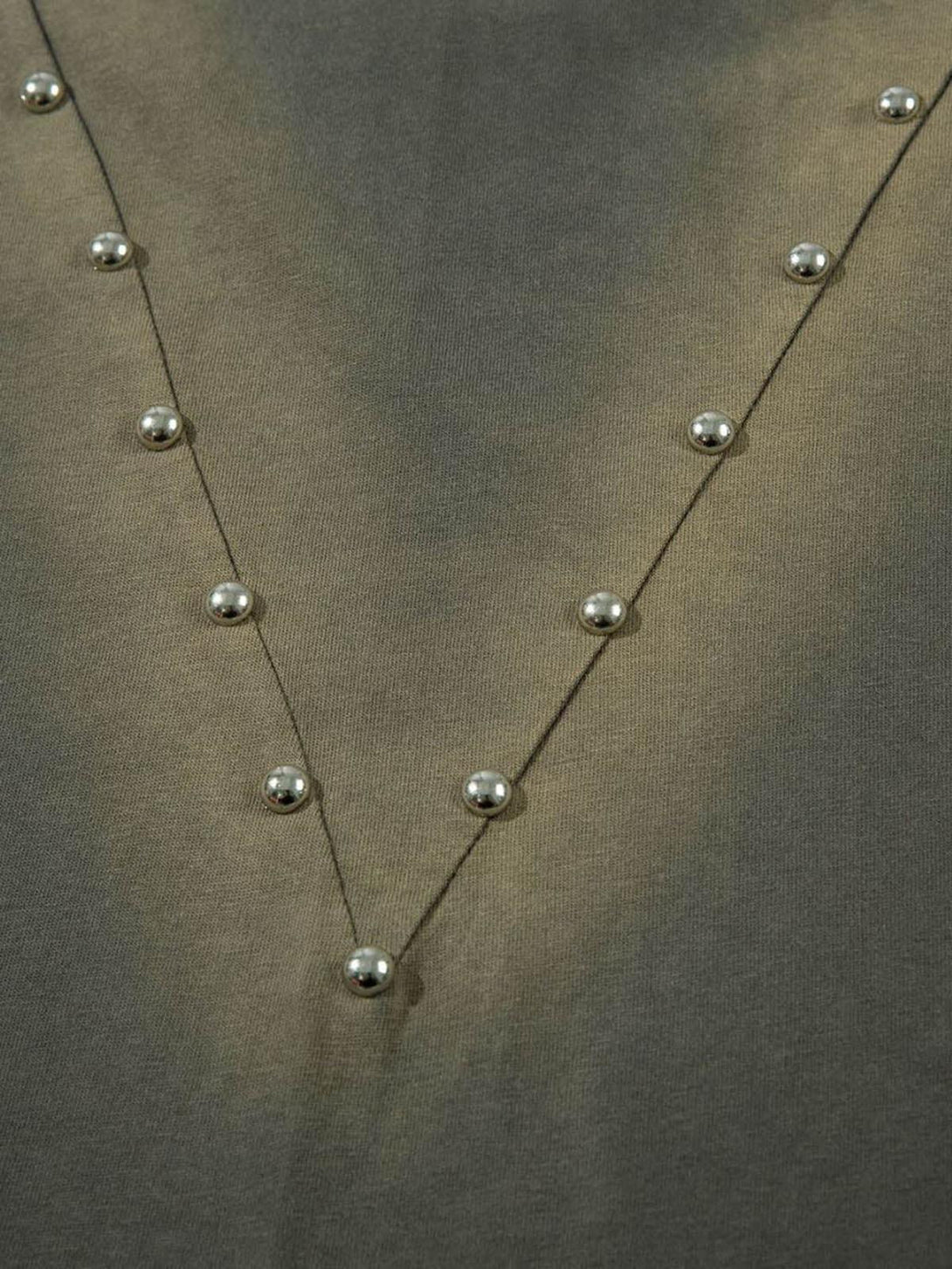 Detailed view of TALISHKO t-shirt highlighting silver studs arranged in a V pattern.