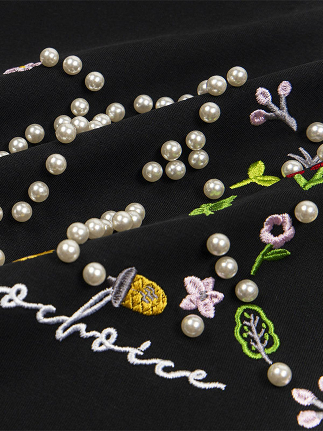 Intricate embroidery and pearl embellishments on a black t-shirt by TALISHKO.