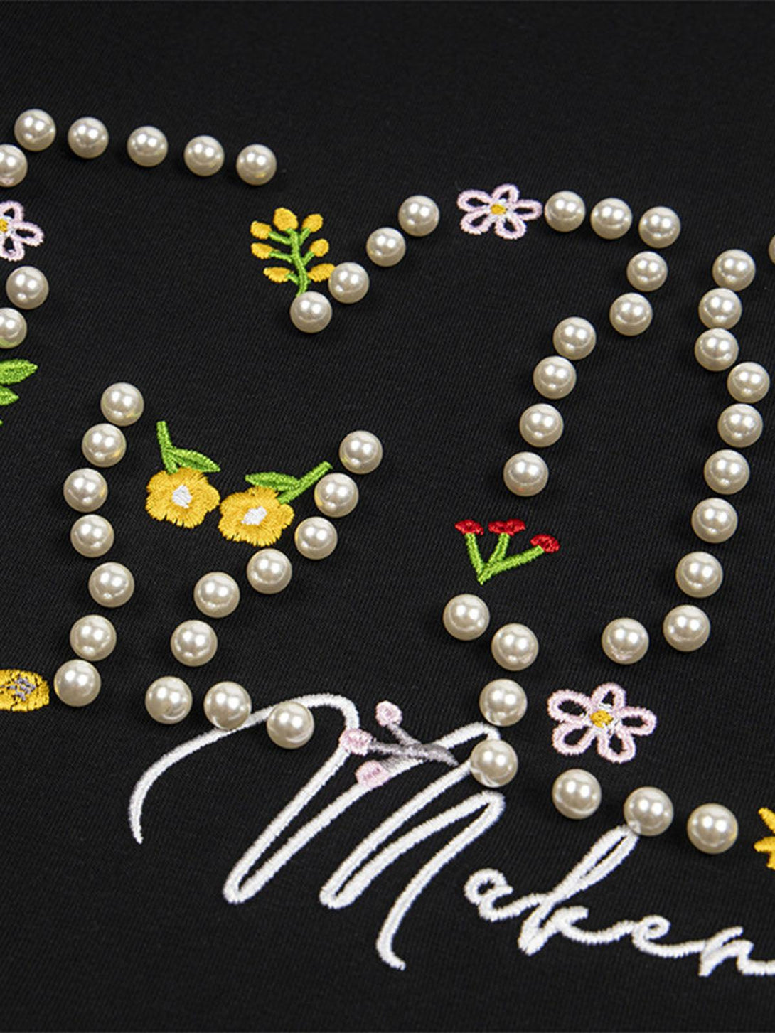 Intricate floral embroidery and pearl accents on a black t-shirt by TALISHKO.