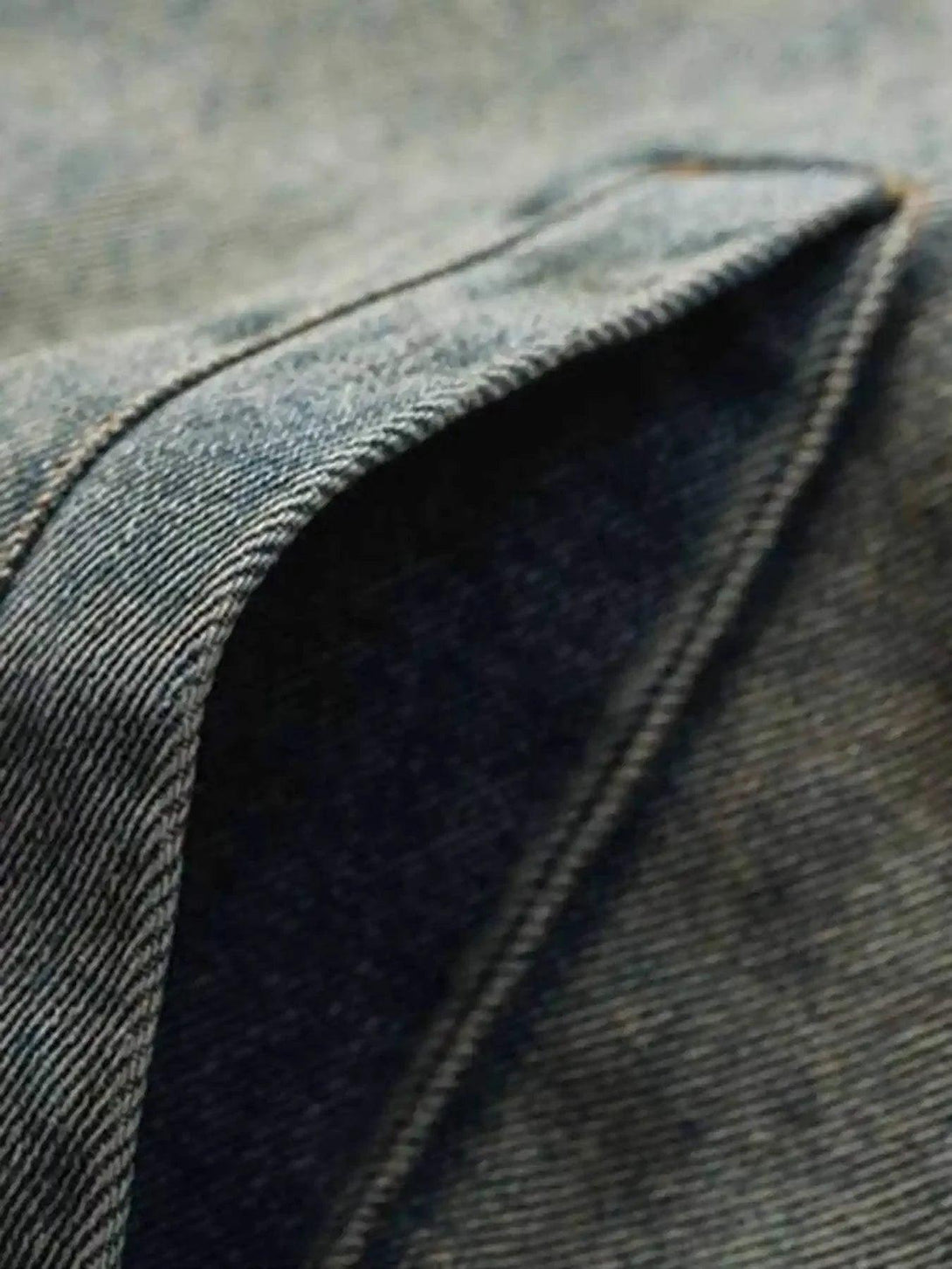 A tight crop highlighting TALISHKO's denim jacket pocket detail and textured stitching.