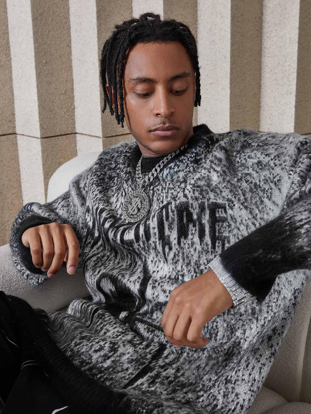 Model relaxing in a TALISHKO oversized spider sweater, highlighting its unique pattern and style.