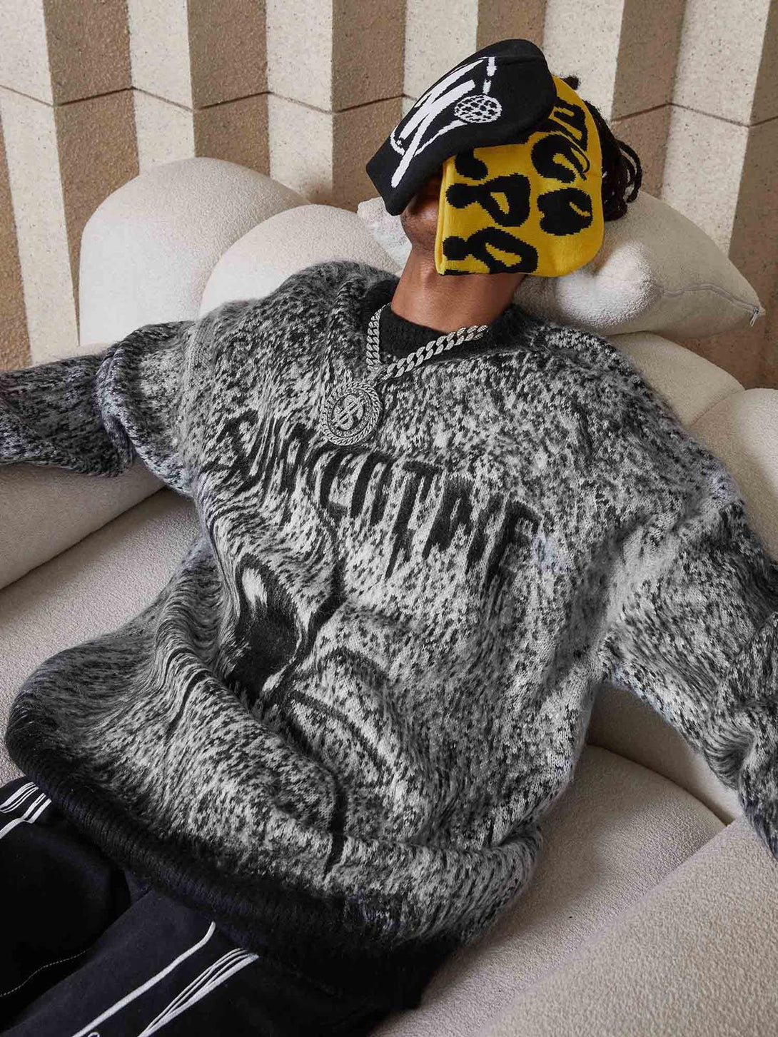 Model lounging in a TALISHKO oversized sweater, featuring a bold spider design and cozy fit.