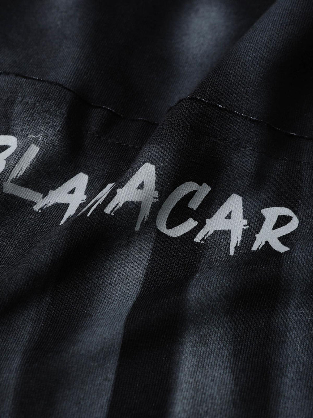 Close-up of embroidered lettering on a TALISHKO oversized tie-dye T-shirt, showcasing texture.