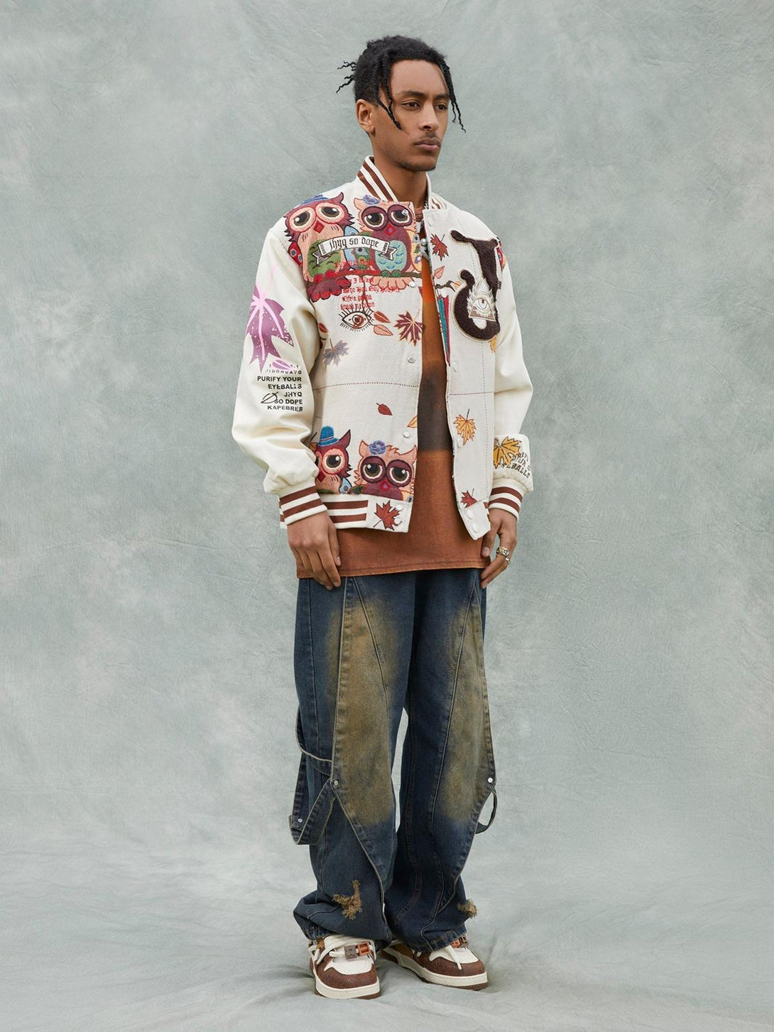 Model styled in a TALISHKO embroidered baseball jersey with owl patches, paired with loose jeans.