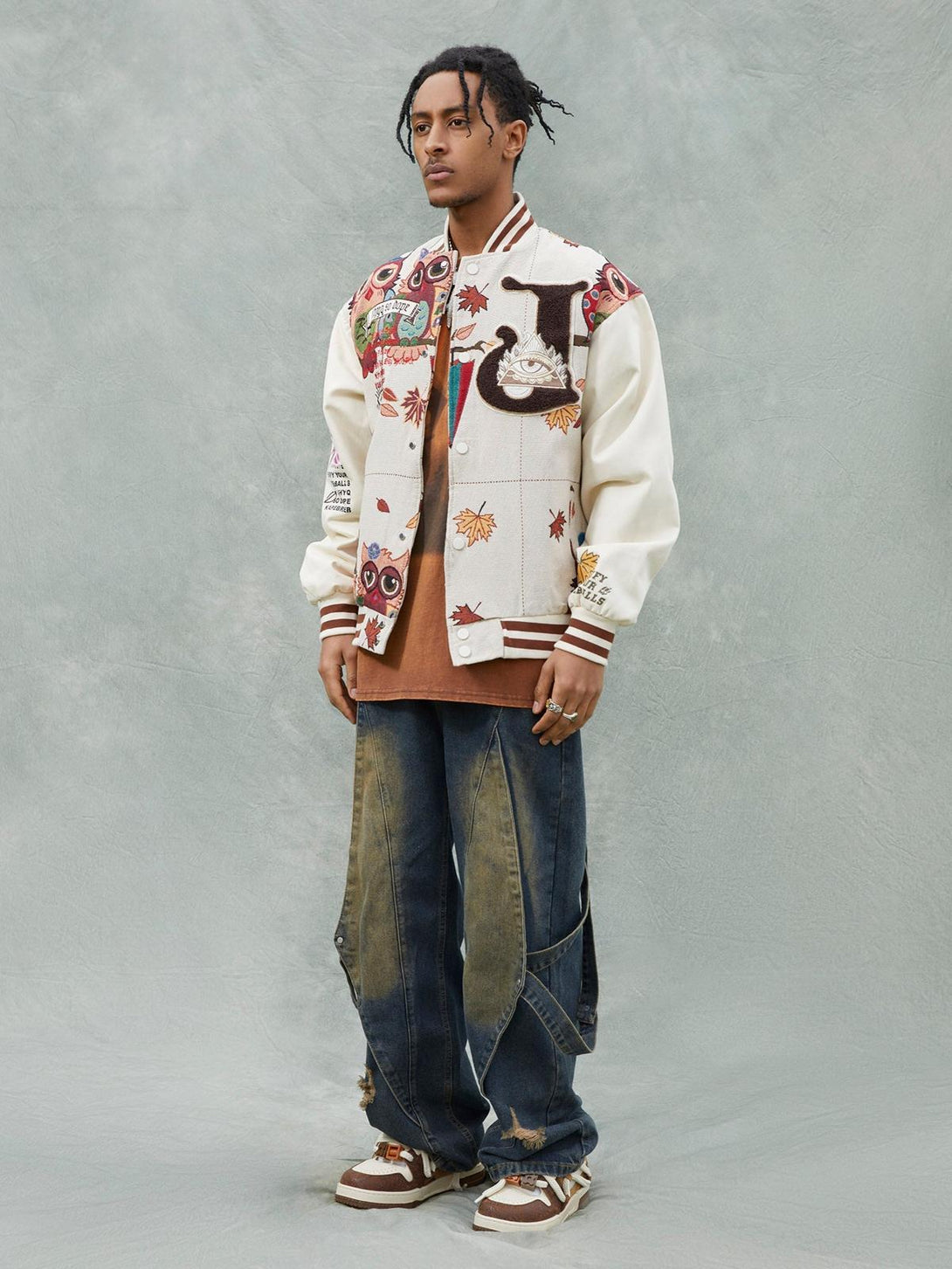 Model in TALISHKO owl patch baseball jersey with intricate embroidery, styled with baggy jeans.