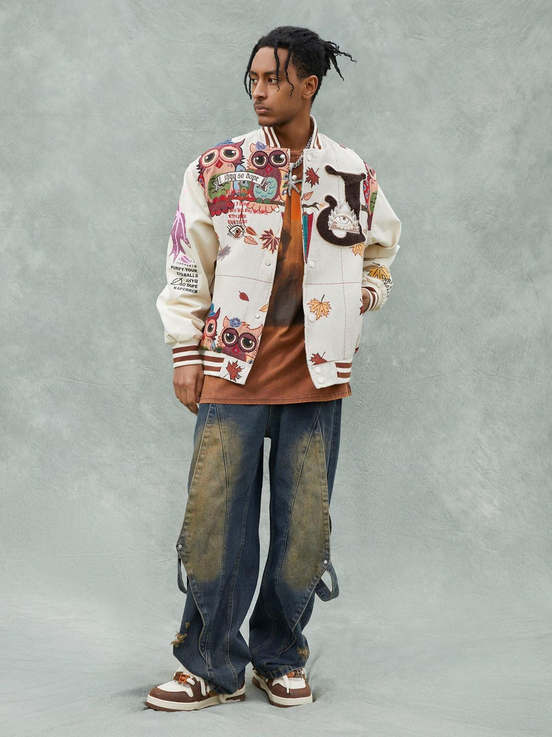 A model styled in a TALISHKO embroidered baseball jersey with owl patches, paired with casual jeans.
