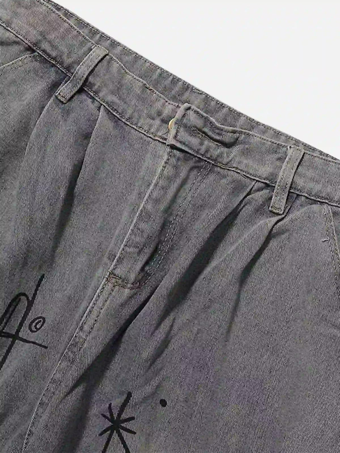 A detailed view of artistic designs on gray TALISHKO cargo jeans, highlighting front fabric texture.