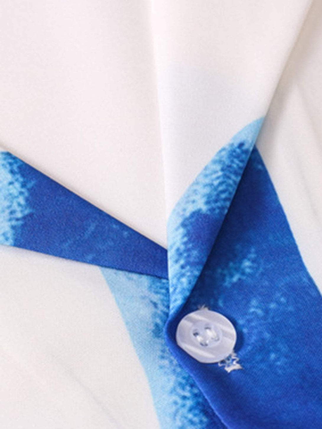 A detailed view of TALISHKO's blue palm print on a short sleeve shirt, highlighting button detail.