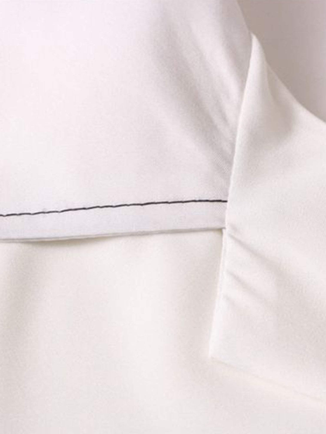 Detailed fabric and stitching on TALISHKO's white short sleeve shirt, emphasizing quality.
