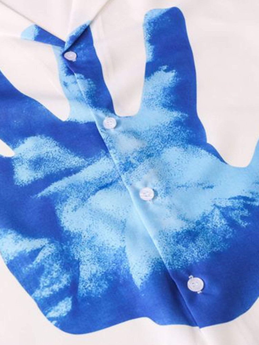 Intricate look at TALISHKO's blue palm print on a short sleeve shirt, focusing on button detail.