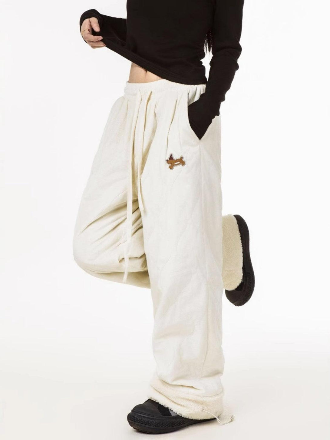 Model in cream paneled padded sweatpants by TALISHKO, highlighting a relaxed, cozy fit.
