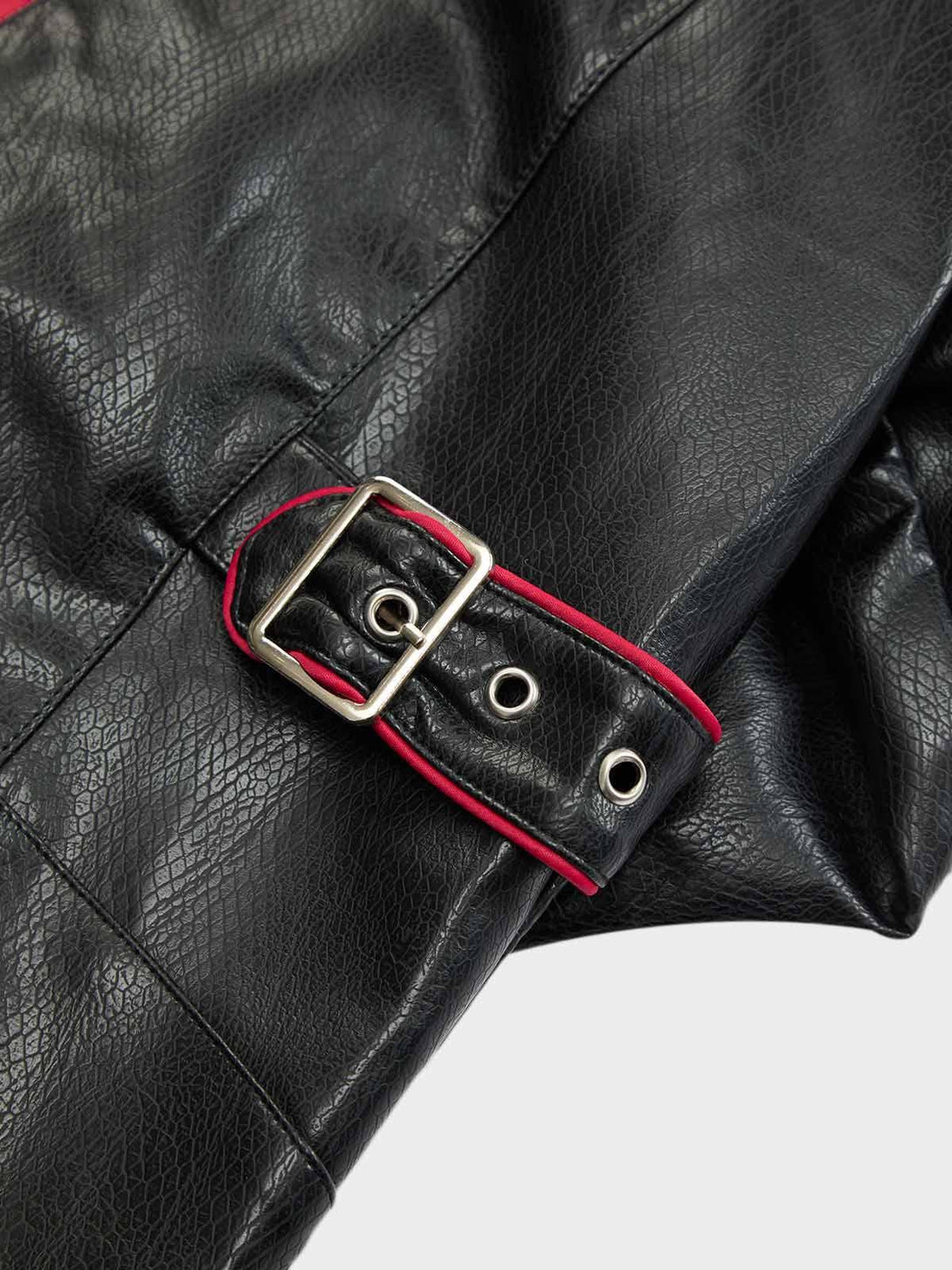 A detailed view of TALISHKO leather biker jacket's buckle and textured material with red accents.