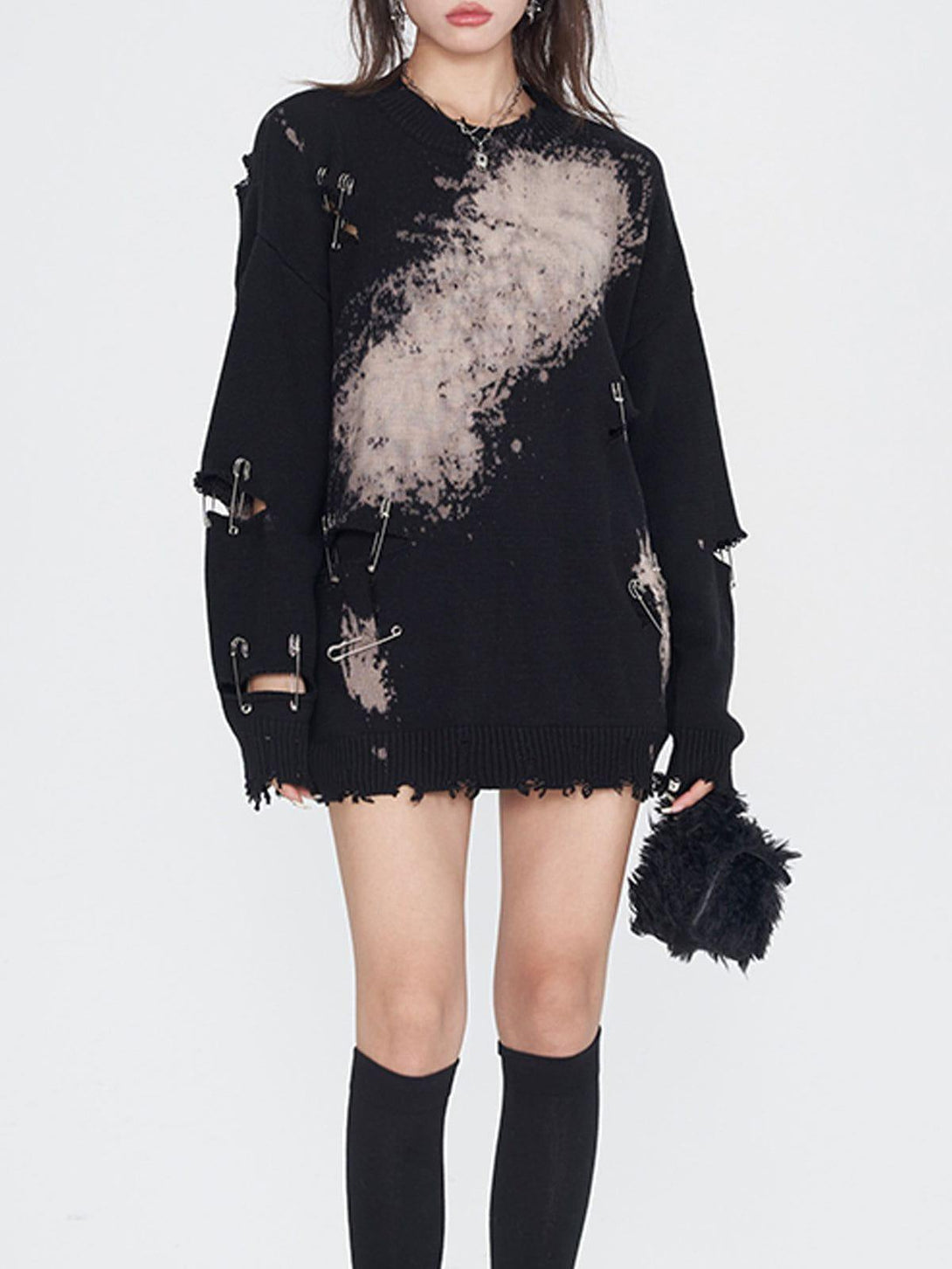 Model showcases TALISHKO's edgy knit sweater with paperclip accents and bleach splatter design.