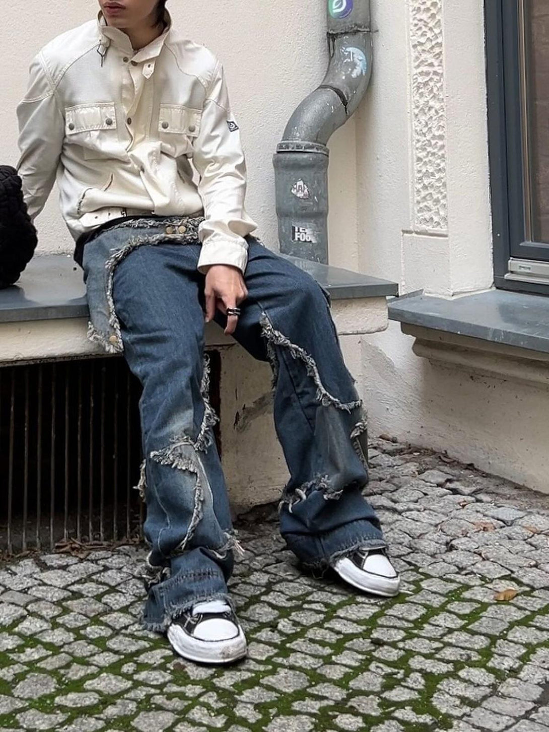 Model wearing TALISHKO patch-embroidered jeans, paired with a white jacket for a casual look.